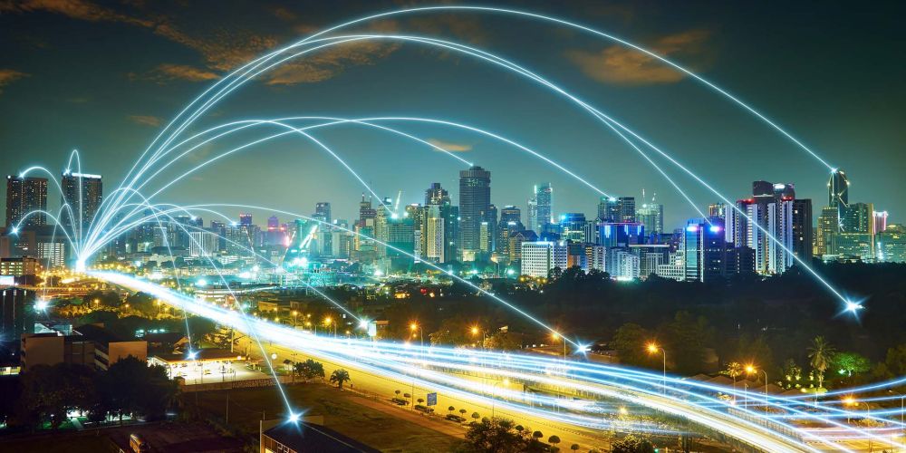 Zeitrafferaufnahme einer Hauptstraße in einer Großstadt bei Nacht mit stilisierten leuchtenden Bögen.