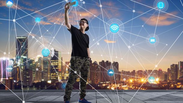 erson hält Handy in die Luft, überlagert von digitalen Symbolen und einer Skyline im Hintergrund.
